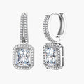 Sterling silver huggie hoops with emerald-cut moissanite drops featuring pavé-set crystals on white background.